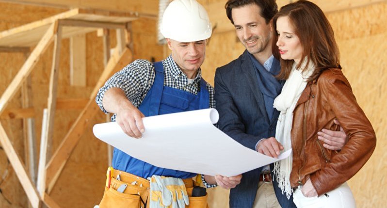 Ein Handwerker zeigt einem Bauherren-Ehepaar einen Bauplan