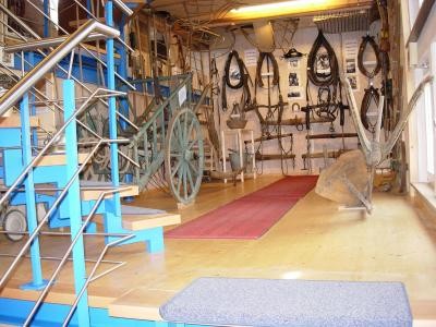 Foto vom Innenraum des Museums mit Pferdegeschirr, Pflug und Leiterwagen