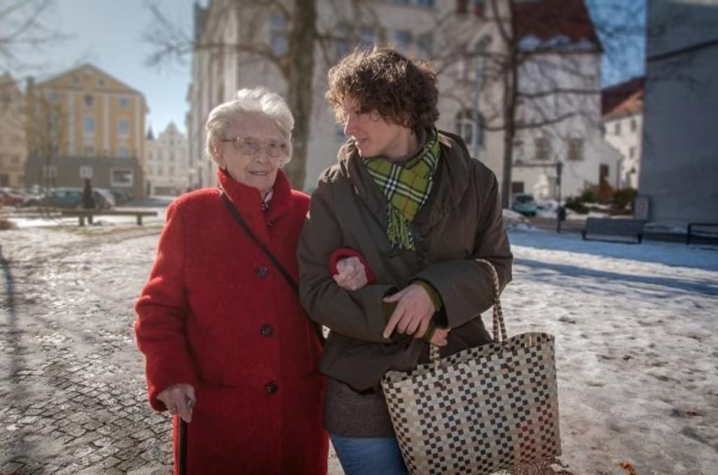 Eine ältere Frau wird von einer anderen Frau beim Einkaufen begleitet