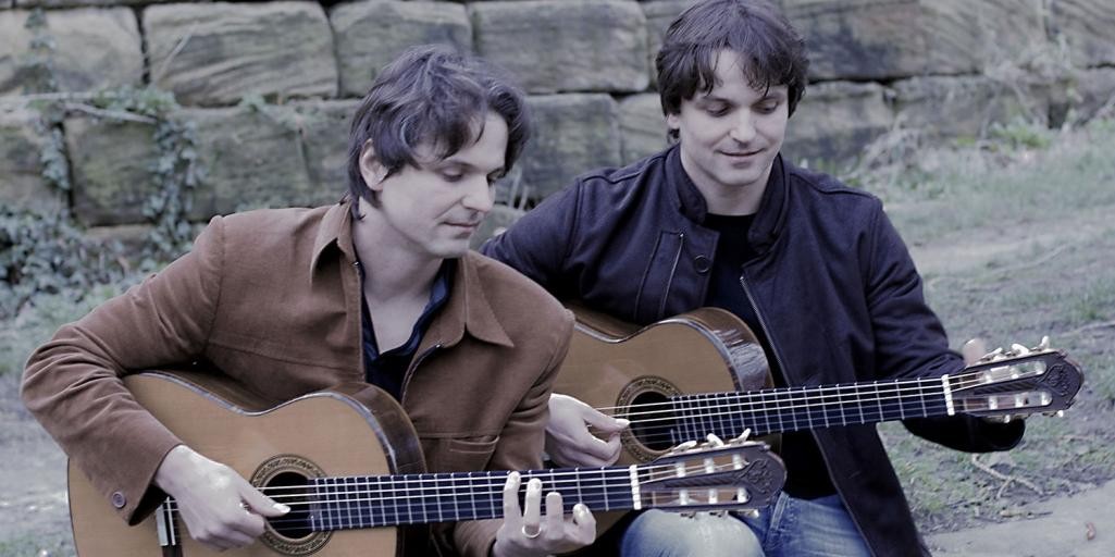 Katona Twins Zwei Männer spielen sitzend Gitarre