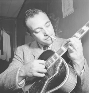 Django Reinhardt spielt eine Zigarette rauchend Gitarre (schwarzweiss)