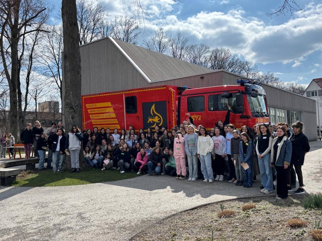 Eine Gruppe von Mädchen und Frauen vor einem Feuerwehrfahrzeug