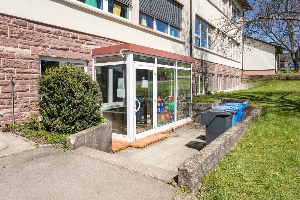 Der Eingang eines Schulgebäudes mit gegliederter Fassade und Windfang.