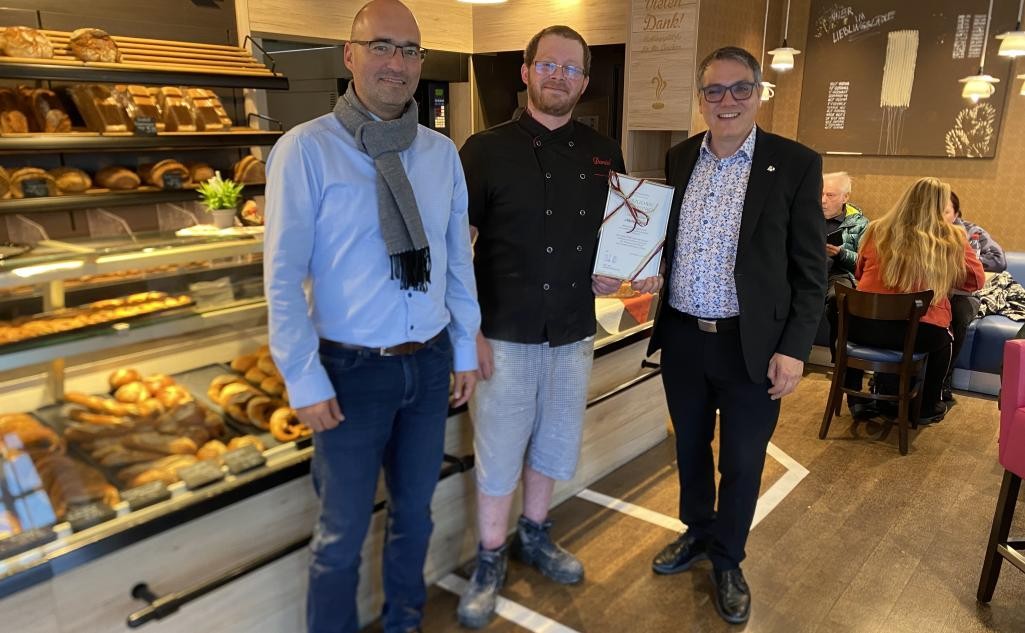 Drei Menschen stehen in einem Bäckerladen und lassen sich abfotografieren. Drei Menschen stehen in einem Bäckerladen und lassen sich abfotografieren.