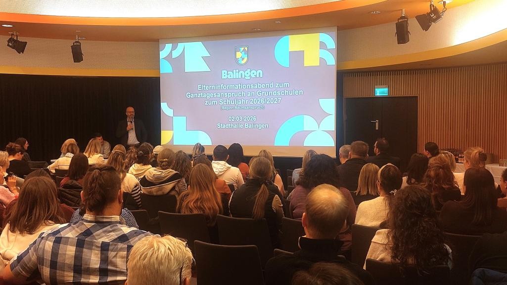 Eine sitzende Gruppe von Menschen, die auf eine Leinwand schaut und einem Redner zuhört