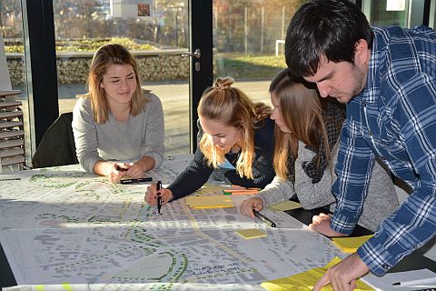 2 Kinder und 2 Erwachsene über einem Plan