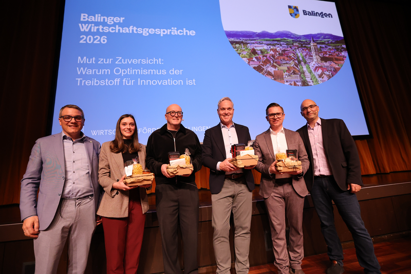 Eine Frau und 5 Männer stehen vor der Leinwand mit Geschenkekörbe in der Hand