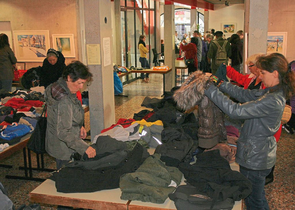 Frauen stöbern in ausgelegten Fundsachen im Foyer des Rathauses