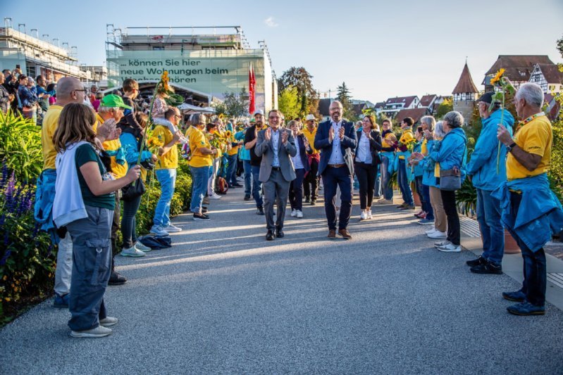 Eine Gruppe Menschen bildet ein Spalier, durch das eine andere Gruppe von Menschen geht. Im Hintergrund die Stad Balingen 