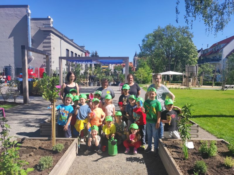 Kinder und Erwachsene stehen an den Hochbeeten Kinder und Erwachsene stehen an den Hochbeeten