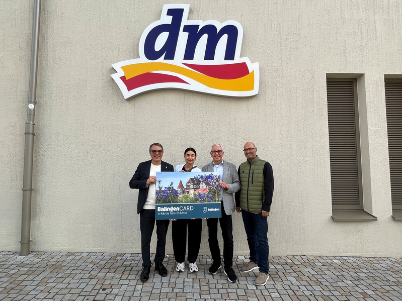 Drei Männer und eine Frau stehen mit einer übergroßen BalingenCard vor der dm-Fliliale