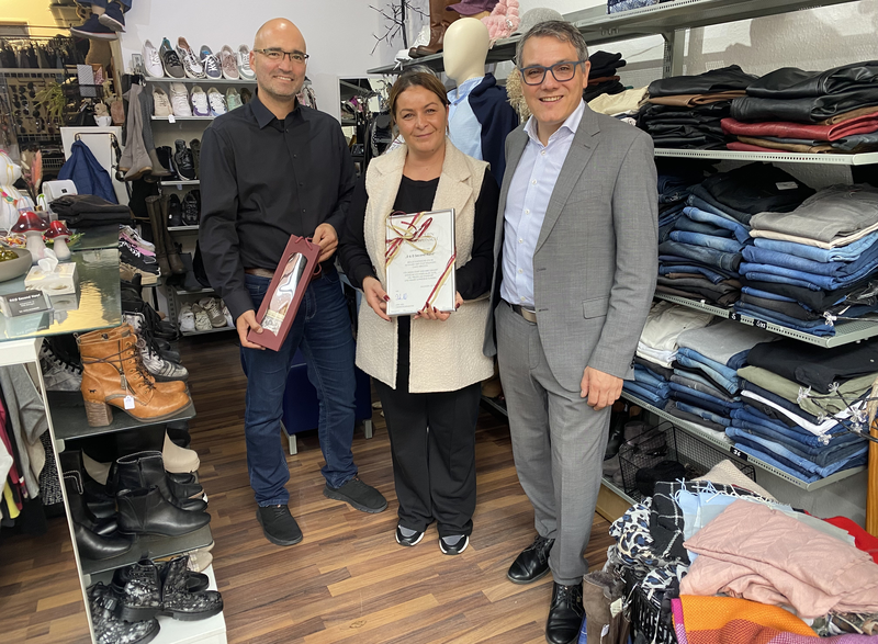 Zwei Männer mit einer Frau in der Mitte in ihrem Second Hand Laden