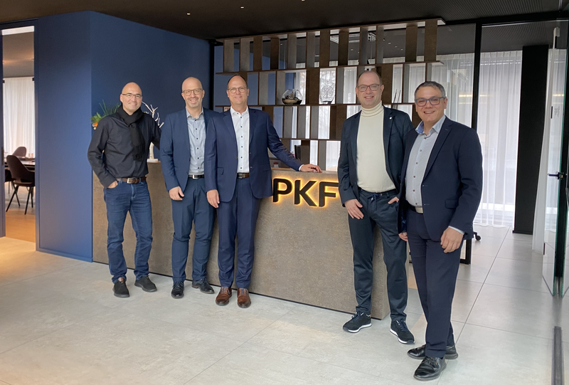 5 Personen stehen an der Theke mit dem PKF Logo